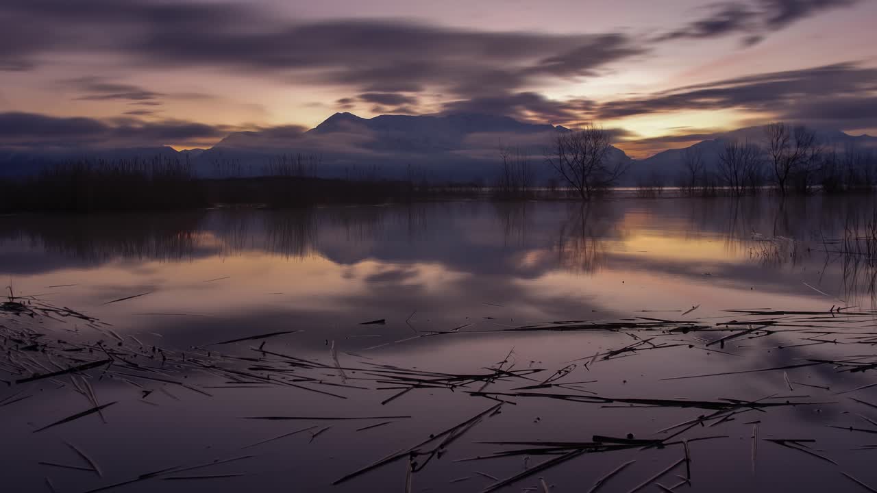 восход солнца таймлапс озера от темноты до рассвета с драматическим облачным пейзажем, отражающимся от поверхности воды - широкоугольное скольжение
