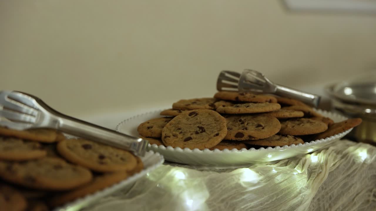 Plate Of Chocolate Chip Cookies With Serving Tongs On Table