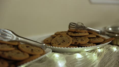 Teller-Mit-Chocolate-Chip-Cookies-Mit-Servierzange-Auf-Dem-Tisch