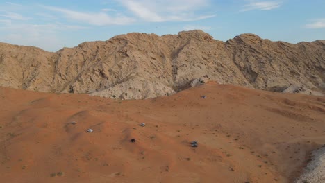 drone view of desert safar, offroading in sharjah's mleiha desert, group of 4x4 vehicles rides on desert dunes, mleiha mountains, 4k footage