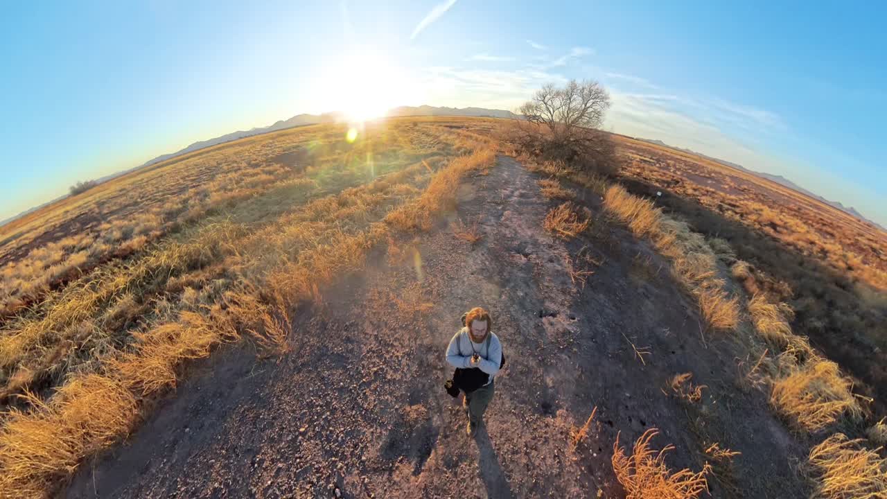 Red haired male walking down dirt path in Arizona Grasslands