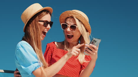 two women looking at phone outdoors