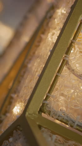 close-up of intricate gold frame with detailed pattern glowing warmly, surrounded by blinking white lights, the blurred background features circular bokeh