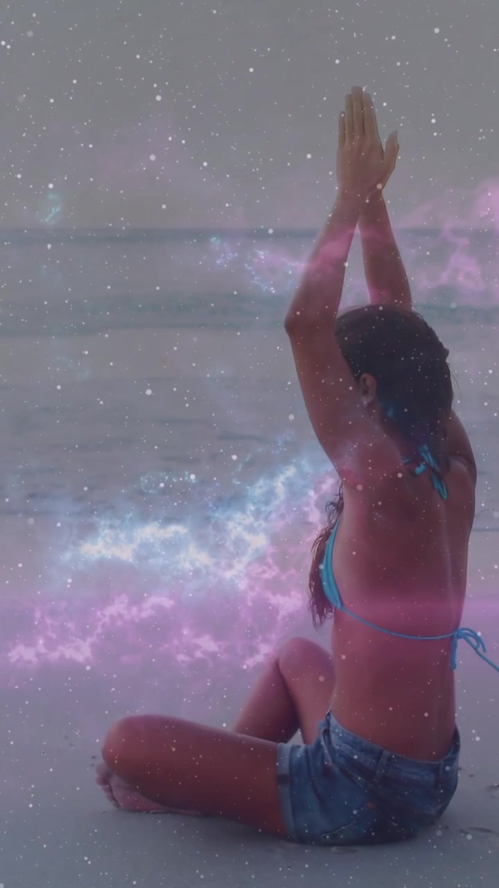 Donna seduta sulla riva che alza le braccia e unisce i palmi, avviando una sovrapposizione di nebulosa benessere.