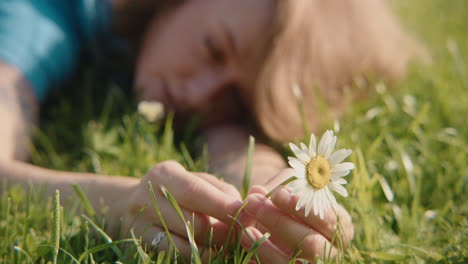 woman lying in grass holding a daisy