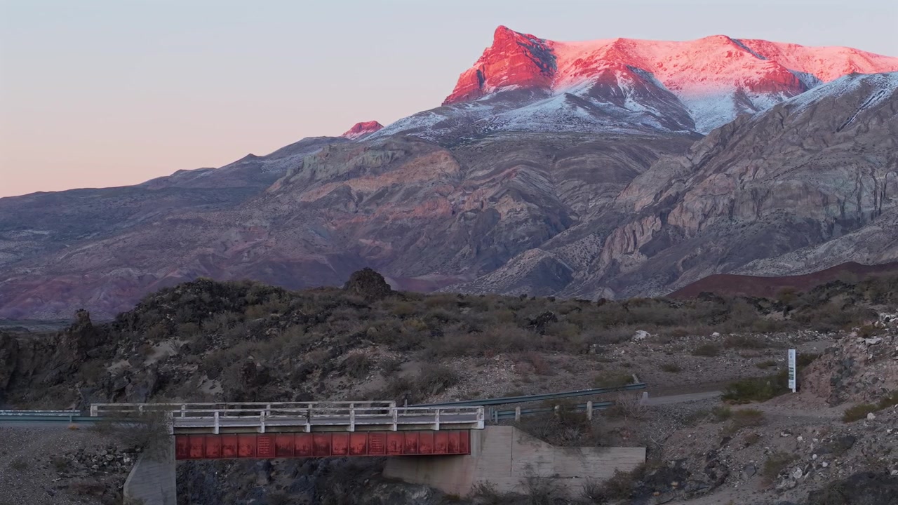 Paesaggio di canyon vulcanico nella Riserva Provinciale La Payunia vicino al vulcano Payún Matrú, Mendoza, Argentina, con terreno lavico eroso, aspre pendici andine e un ponte alla luce dell'alba, movimento scorrevole del drone.