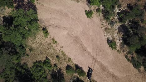 Un-Dron-Disparó-A-Un-Vehículo-De-Safari-Navegando-A-Través-De-Un-Lecho-De-Río-Seco-Bajo-El-Caluroso-Sol-De-La-Tarde-En-África