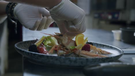 a professional italian chef is preparing a tasty fish plate with scampi, salad and fruits - 02