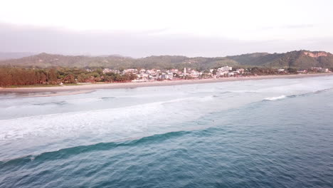 Die-Wunderschöne-Insel-Ecuador-Mit-Blauem,-Ruhigem-Meer-Mit-Verschiedenen-Häusern-Und-Grünen-Bäumen---Luftaufnahme