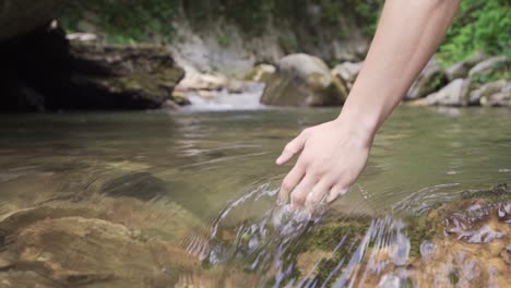 El-Toque-De-La-Mano-Al-Agua-Que-Fluye-En-El-Arroyo.-Camara-Lenta.