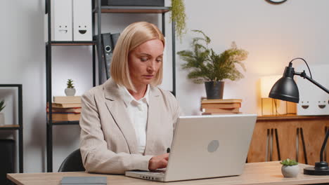 happy mature caucasian businesswoman freelancer in formal suit showing thumb up at home office desk