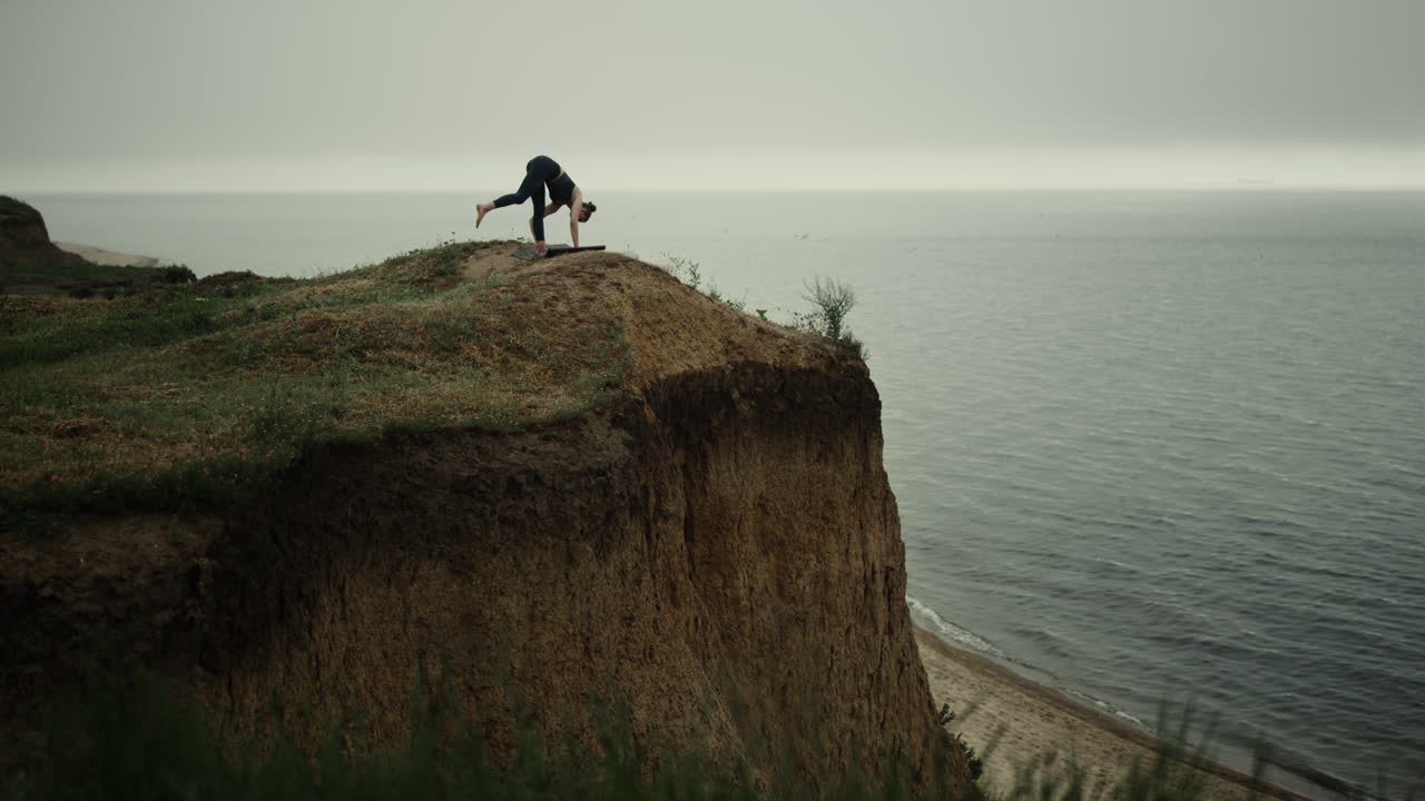 спортивная девушка поднимает ногу к небу, стоя на высоком холме. гибкая женщина растягивает тело.