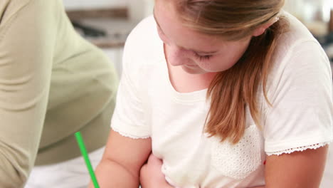 Mother-using-laptop-and-her-daughter-drawing