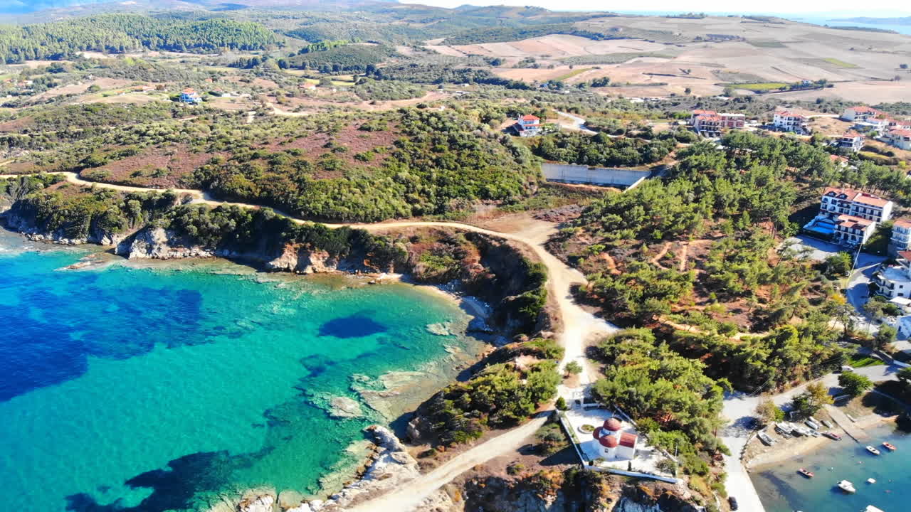 Vista aérea con dron de Nea Roda, situada en la costa del mar Egeo, Grecia. Varios edificios con vegetación, iglesia cerca de la costa.