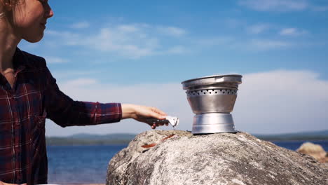 Schwedisches-Mädchen-Setzt-Die-Pfanne-Eines-Tragbaren-Trangia-kochers-Auf,-Um-Am-See-Zu-Kochen