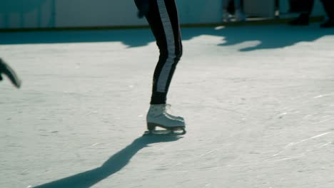 a girl skating with a free style movement in the ice surface with her friends during sunny day - wide shot