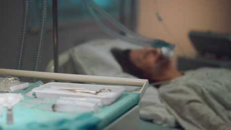 máscara de oxígeno paciente acostado en una sala de hospital vacía. mesa de herramientas médicas de cerca.