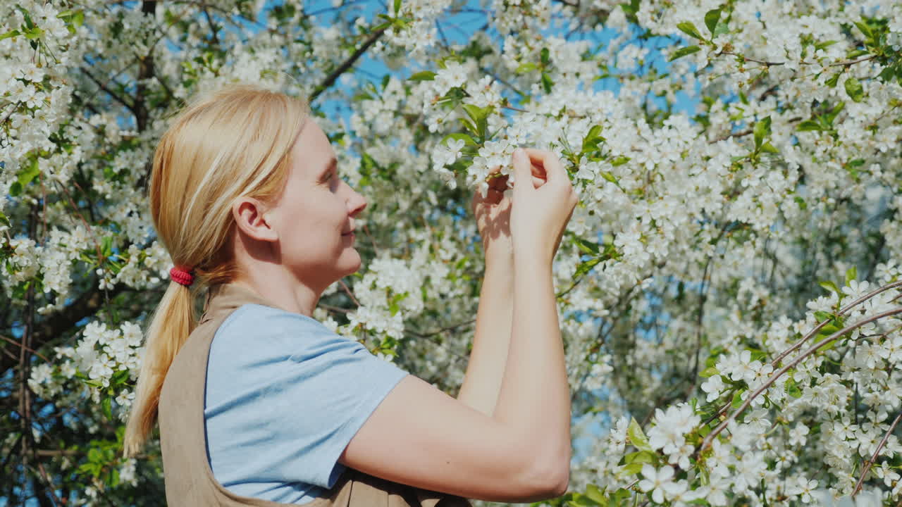una joven admira un árbol en flor la llegada de la primavera y el calor