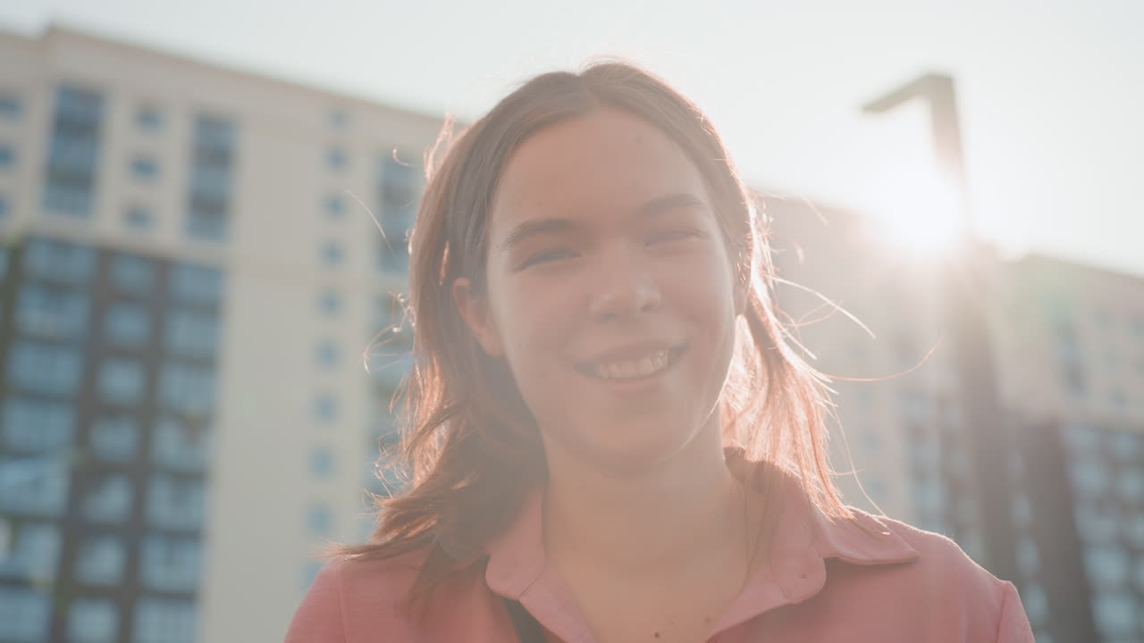 Woman Smiling Warmly With Skyline In Background, Cheerful Lady Enjoying Sunny Day Against Cityscape Backdrop, Happy Female Subject Illuminated By Sunlight With Bustling City Scene Behind Her