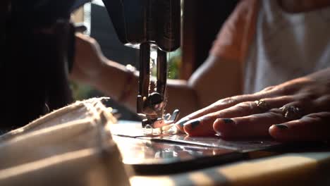 dressmaker sewing on a vintage sewing manual machine on a sunshine morning in agra city, india. - panning shot