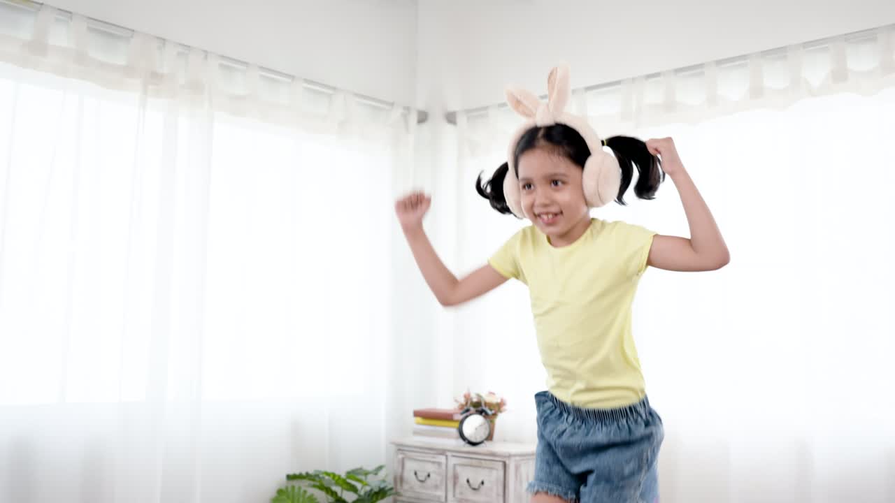 4K 50fps, Haft body cute little girl wearing Asian bunny ears, jumping on her favorite sofa, with a joyful expression on her face, in her bedroom.