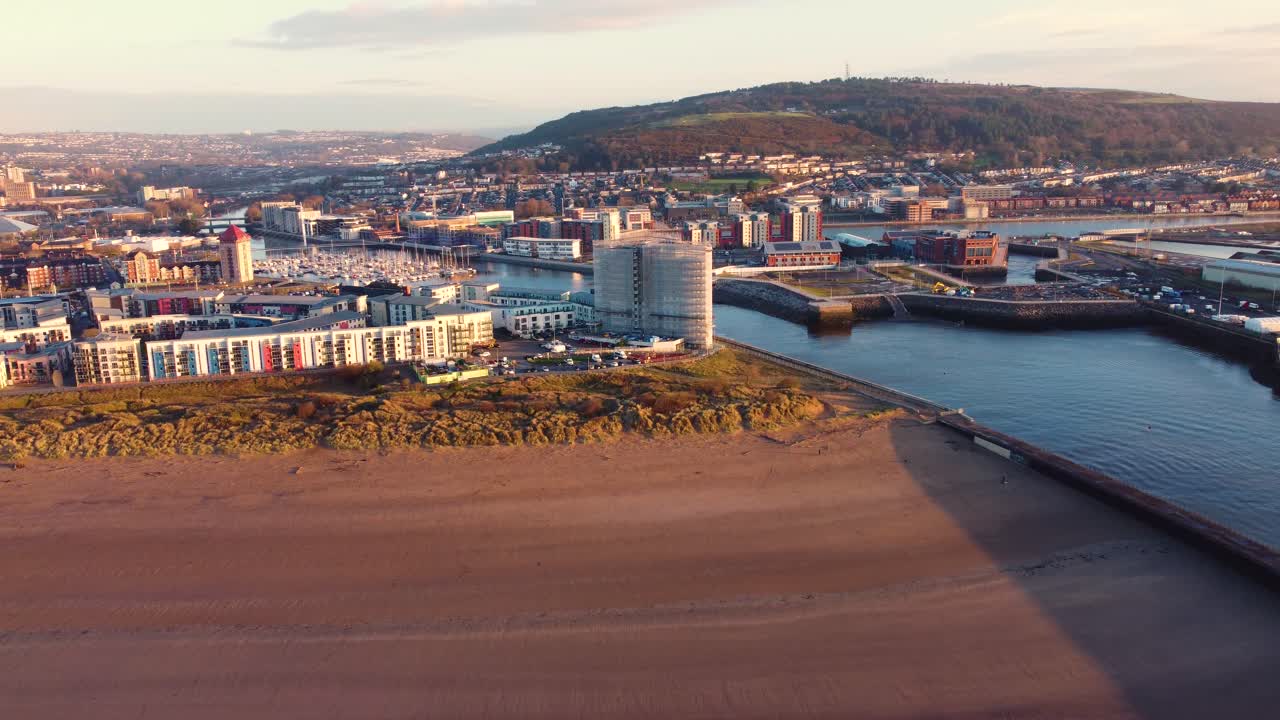 Splendida luce dell'alba sull'ingresso della Marina di Swansea che mostra gli edifici vicini con yacht ormeggiati sullo sfondo. Riprese aeree con drone.