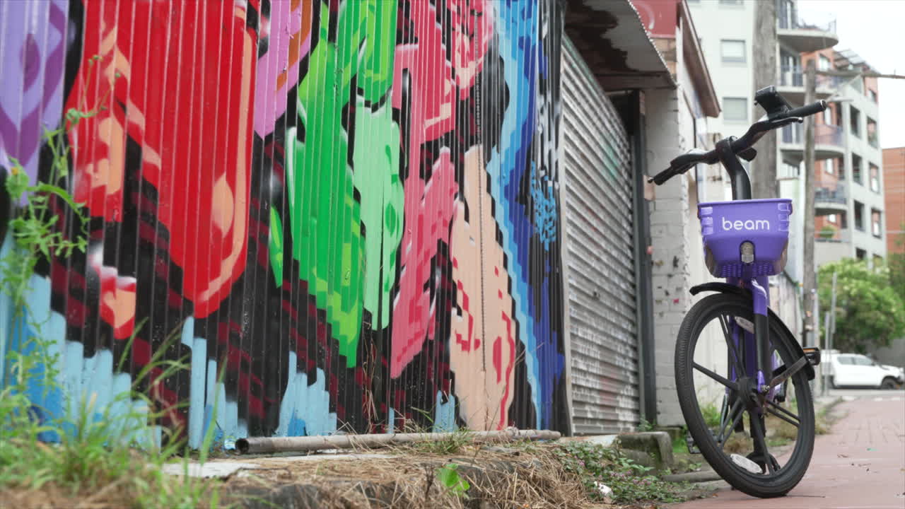 A hire bike stands next to a graffiti'd wall on a quiet urban residential street, innerwest Sydney Australia
