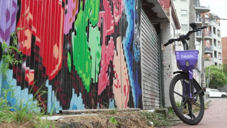 Un-Alquiler-De-Bicicletas-Se-Encuentra-Junto-A-Una-Pared-Pintada-En-Una-Tranquila-Calle-Residencial-Urbana,-El-Interior-Del-Oeste-De-Sydney,-Australia