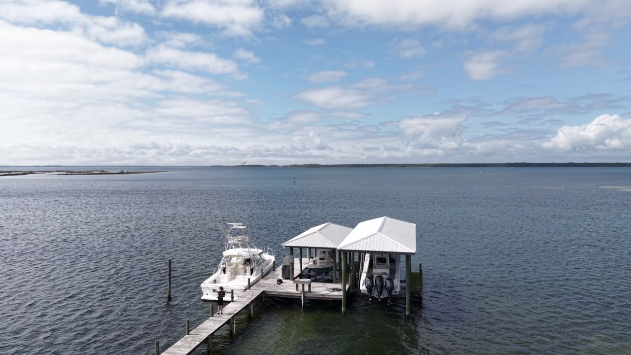 Long wooden pier with boats stretching into calm coastal Grand Lagoon water, 30A, Florida, USA