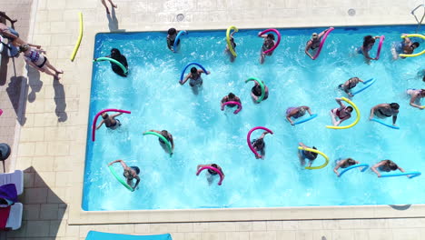 group of women doing aquagym fitness in an outdoor swimming pool. drone view