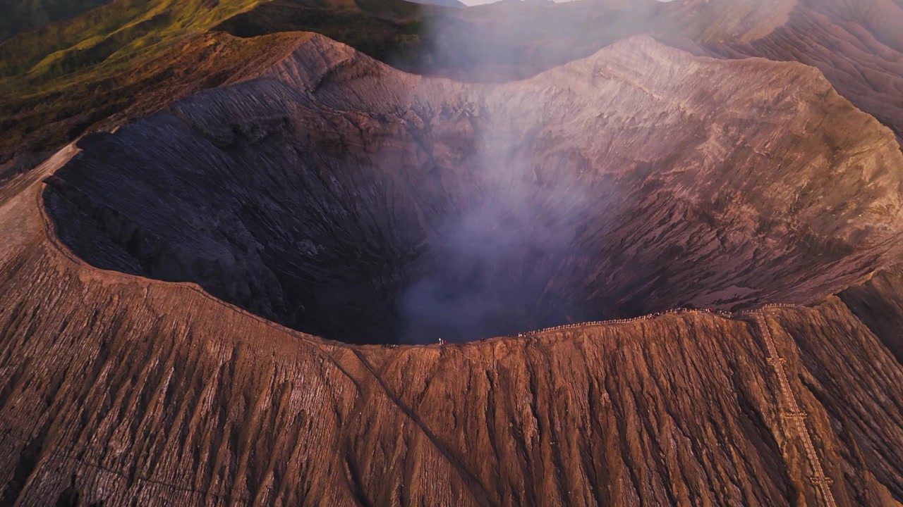 Mount Bromo volcano emit sulfurous fumes with tourists on crater rim, aerial