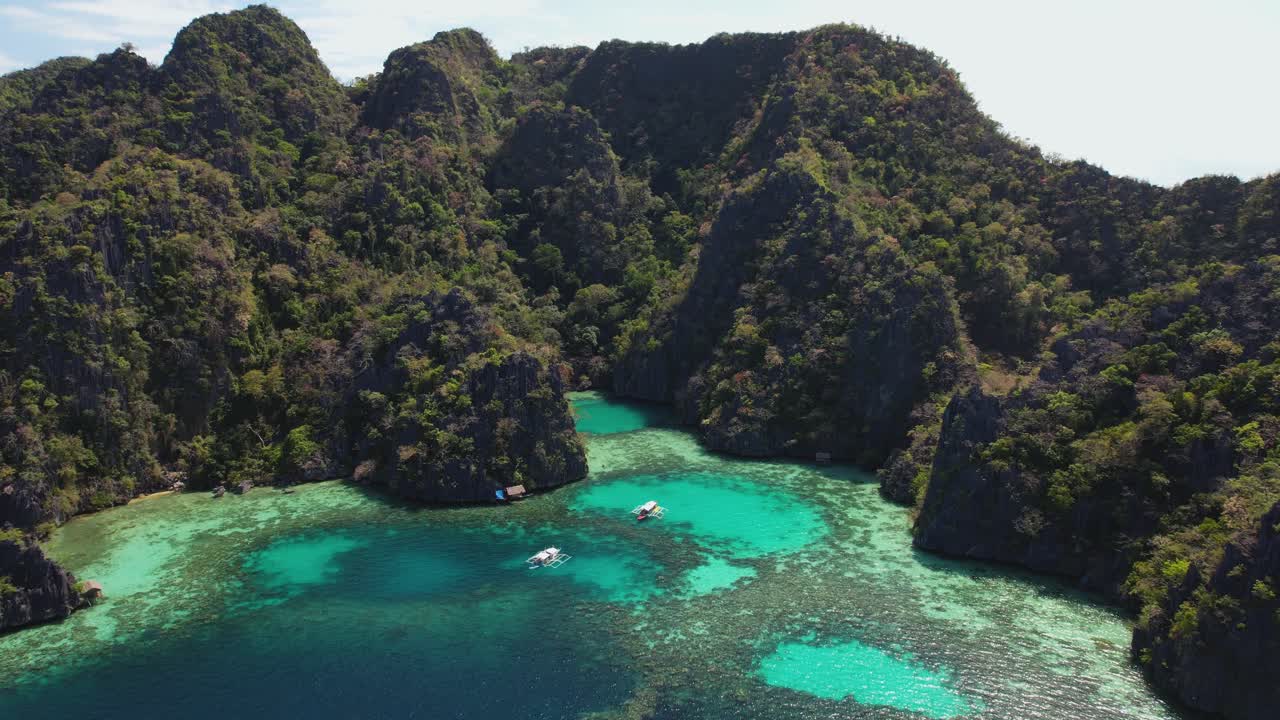 4K drone video showing the beautiful landscape around Green Lagoon near Coron in Palawan, Philippines. This tropical lagoon is surrounded by towering limestone cliffs, islands and beautiful water.