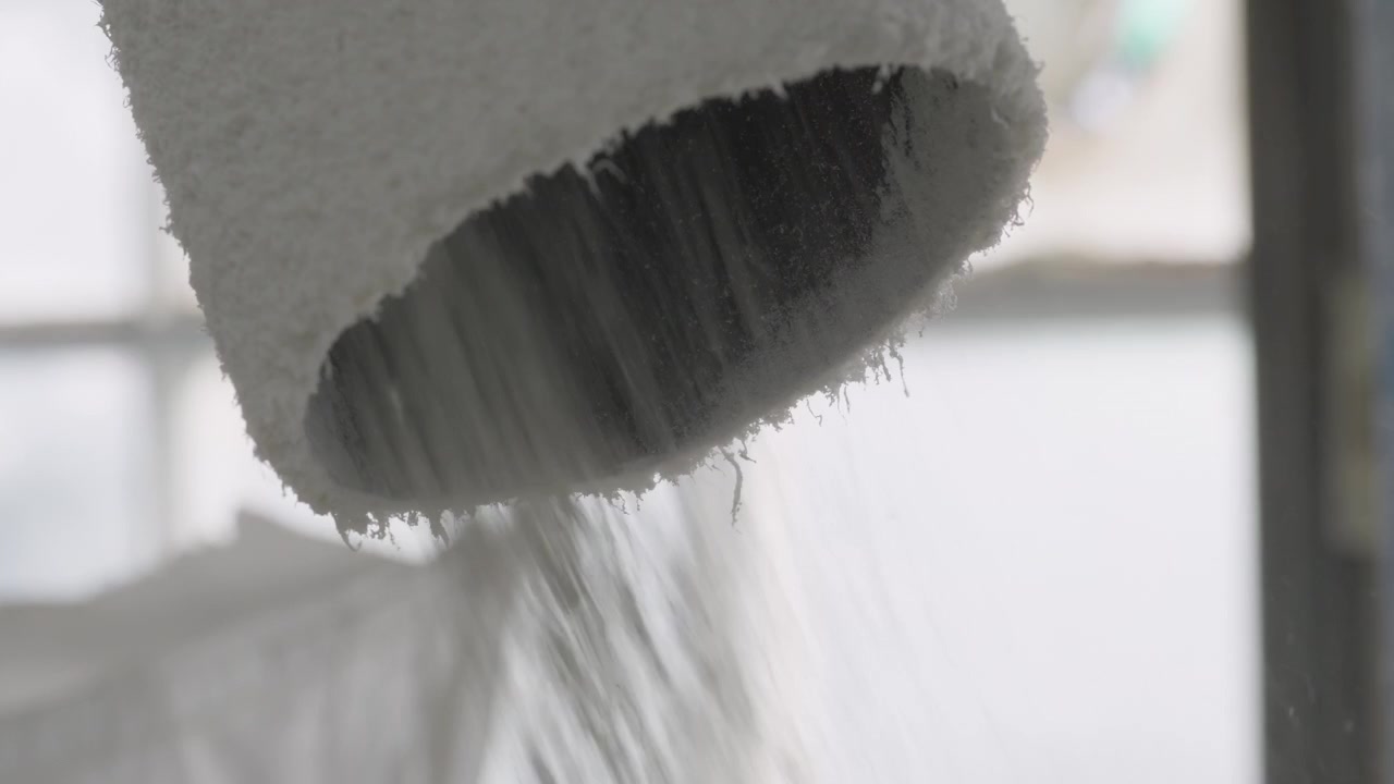 リサイクル施設内で産業用シュレッダーから細断されたプラスチック繊維が流れ出る超クローズアップ。