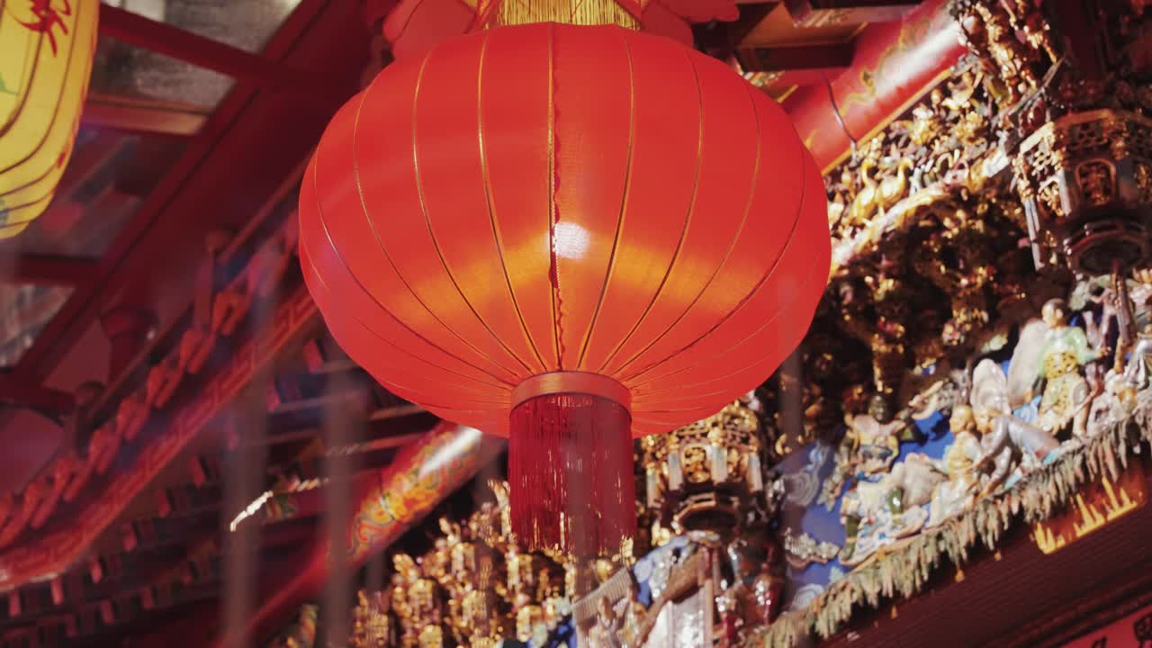 A glowing red Chinese lantern hangs above incense candles at a Taiwanese temple, creating a serene and spiritual atmosphere rich with tradition