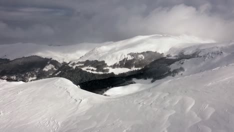 AERIAL---Snowy-winter,-sunny-day-in-the-mountains-of-Kolasin-ski-resort,-Montenegro