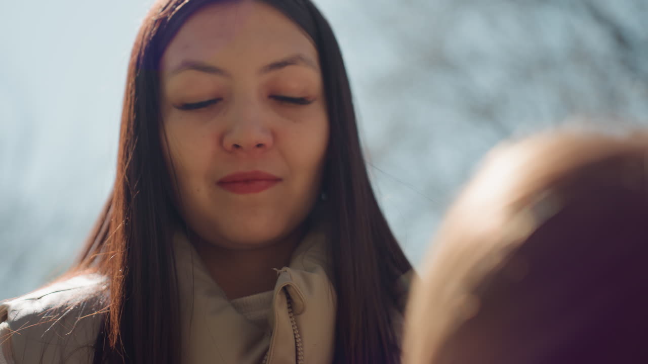 야외에서 꼼꼼하게 머리를 땋는 여성, 야외에서 긴 머리를 조심스럽게 땋는 데 집중하는 여성, 야외에서 정확하고 섬세하게 머리를 땋는 데 집중하는 여성 공연자