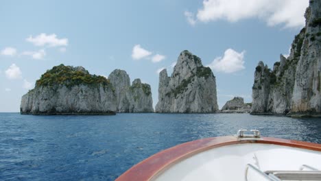 approaching to che famous faraglioni of capri with a wooden boat during a windy day in spring