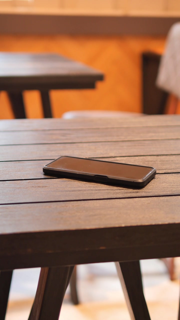 Mobile Phone Lying on an Empty Wooden Table in a Cafe