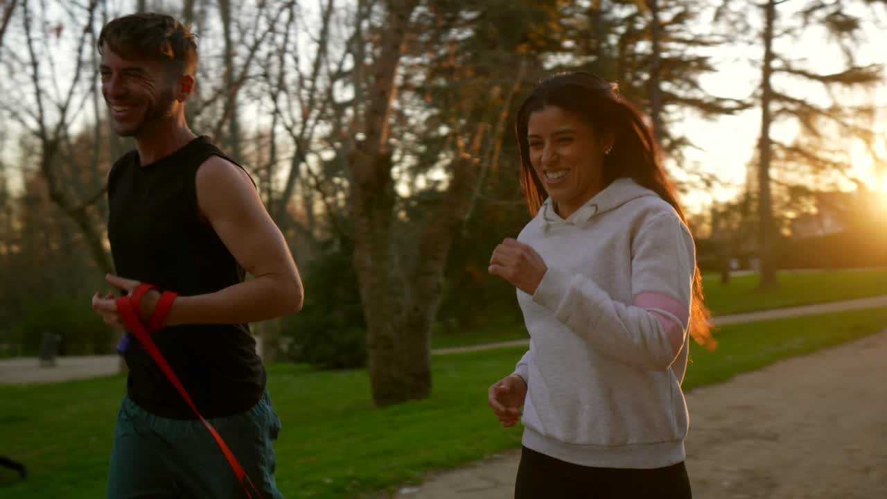 Happy Couple Running with Their Dog in a Park at Sunset