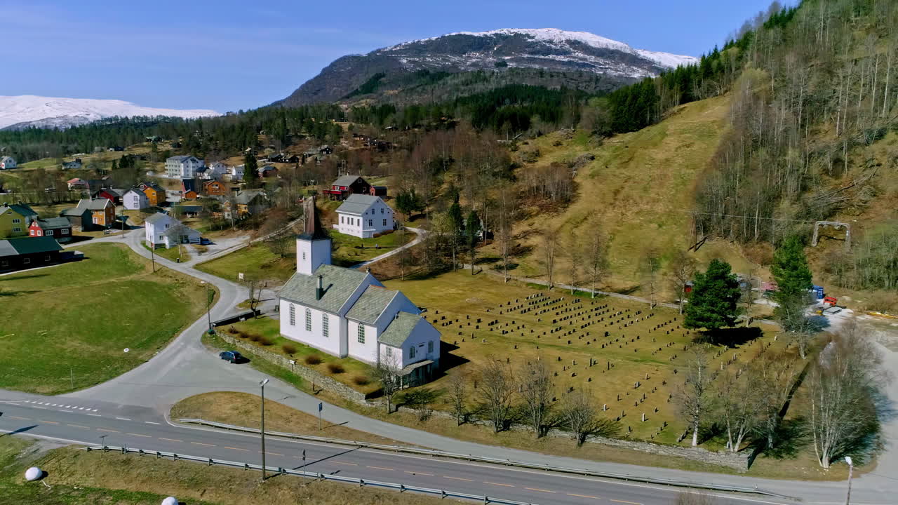 toma aérea de drones de la iglesia y el cementerio de gimsoy en las islas lofoten rodeadas por una red de carreteras en noruega durante el día
