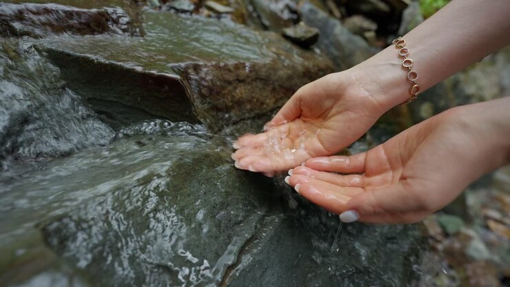 Woman drinking water from a stream