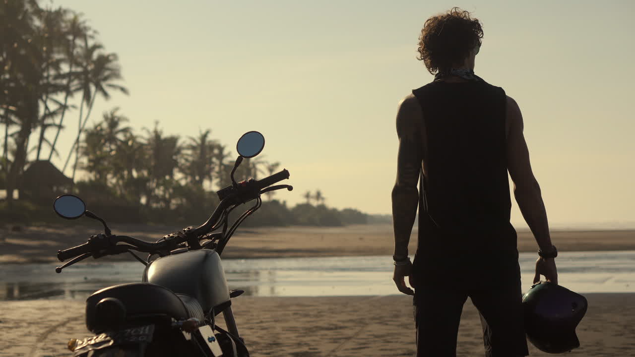 hombre en motocicleta en la playa del amanecer