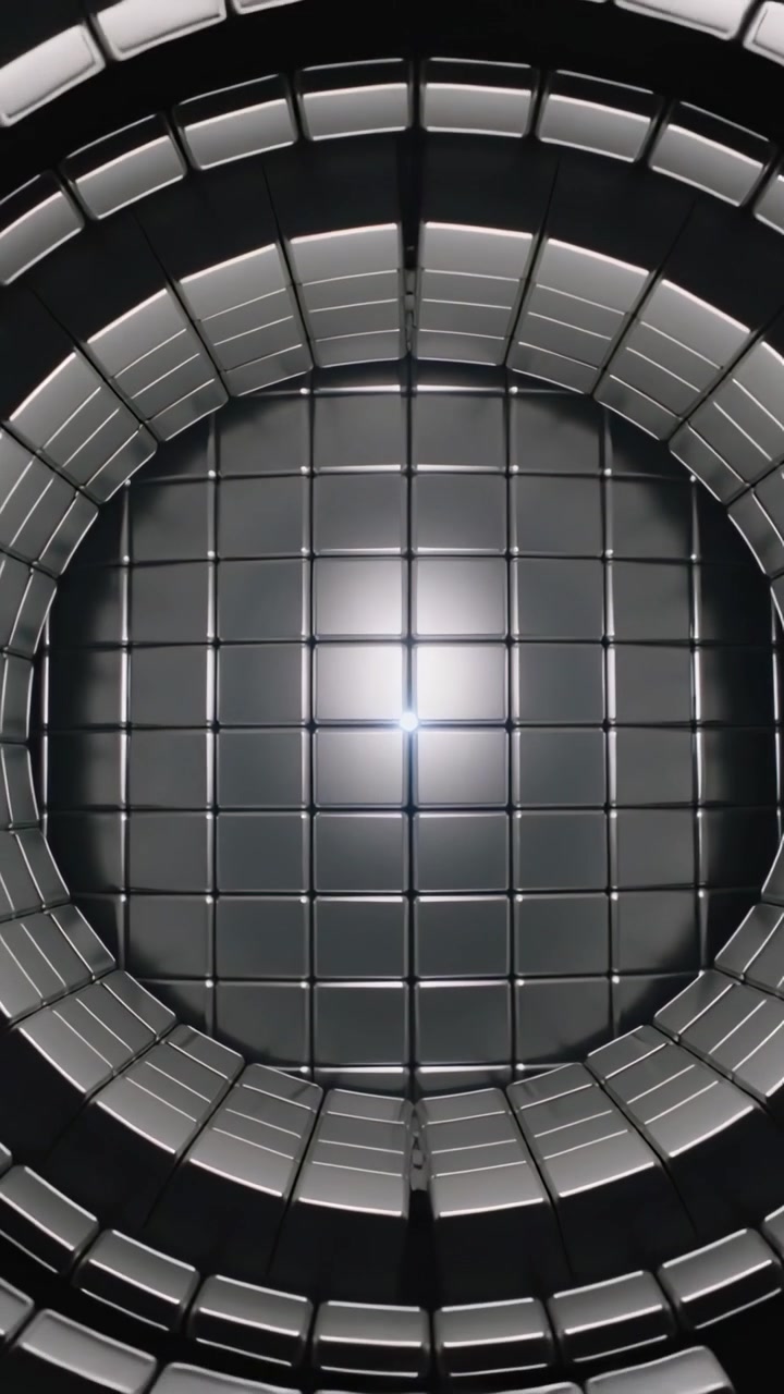 Video vertical: La cámara se aleja, revelando un pozo de azulejos metálicos brillantes para mostrar un destello central luminoso.