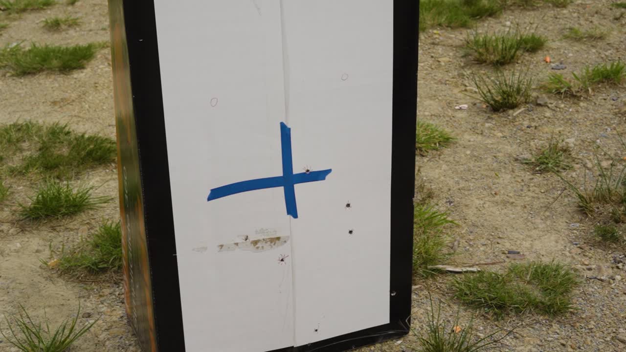 метка в виде синего креста на целевом объекте, стоящем на открытом стрельбище