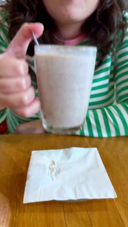 a woman is sitting at a table with a cup of coffee and a spoon