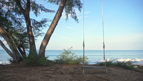 empty swing with blue sea in background. slow-motion