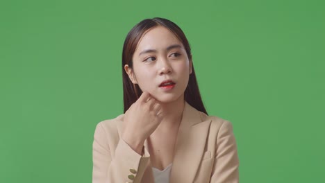 close up of asian business woman thinking about something and looking around then raising her index finger while standing on green screen in the studio