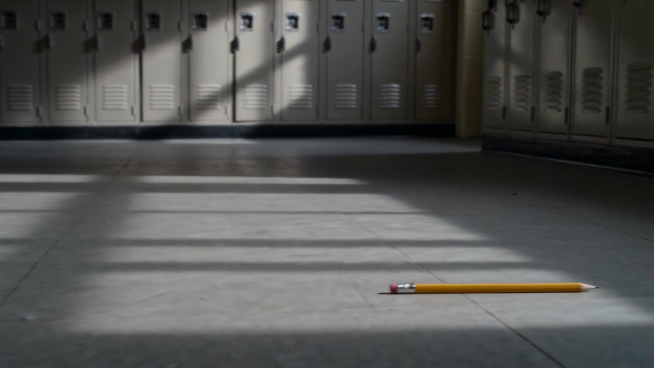 Sliding yellow pencil entering frame moving left across sunlit school hall, lockers, copy space