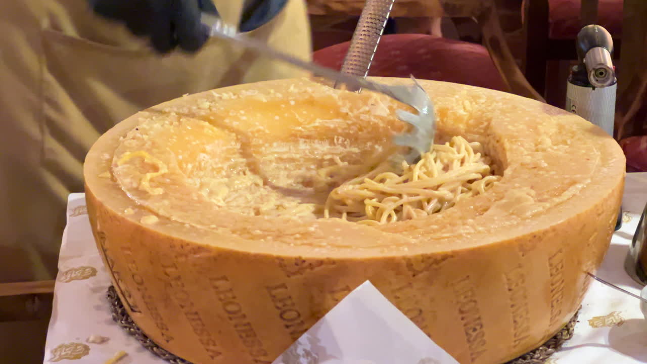 Preparing and mixing traditional Italian parmesan cheese wheel pasta dish at a restaurant, delicious fresh spaghetti, food in Italy, 4K shot
