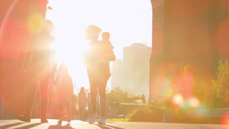 young family walking under a bridge in manhattan, backlit